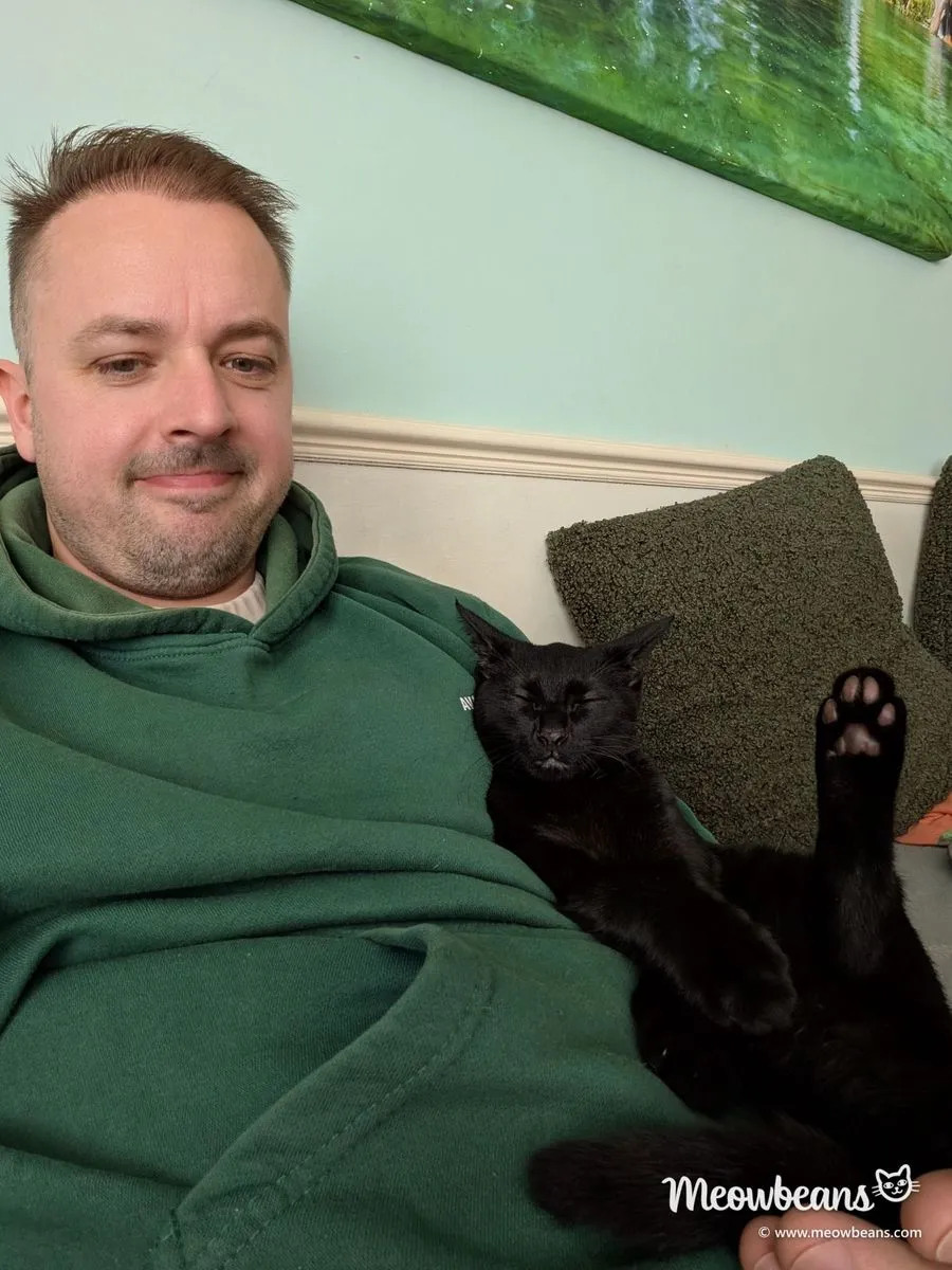 John on the sofa with Jelly Bean, the family's black kitten